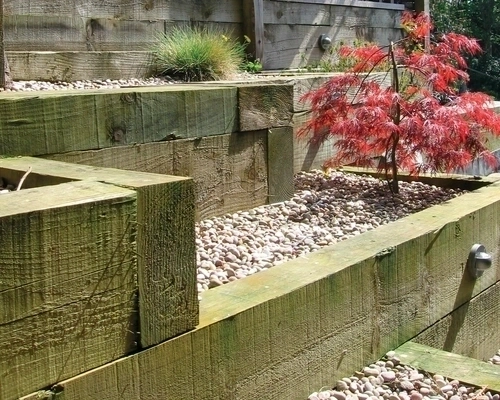 Hardwood timber sleeper used in a garden with flowers scattered around it. Hardwood timber sleeper used in a garden with flowers scattered around it.